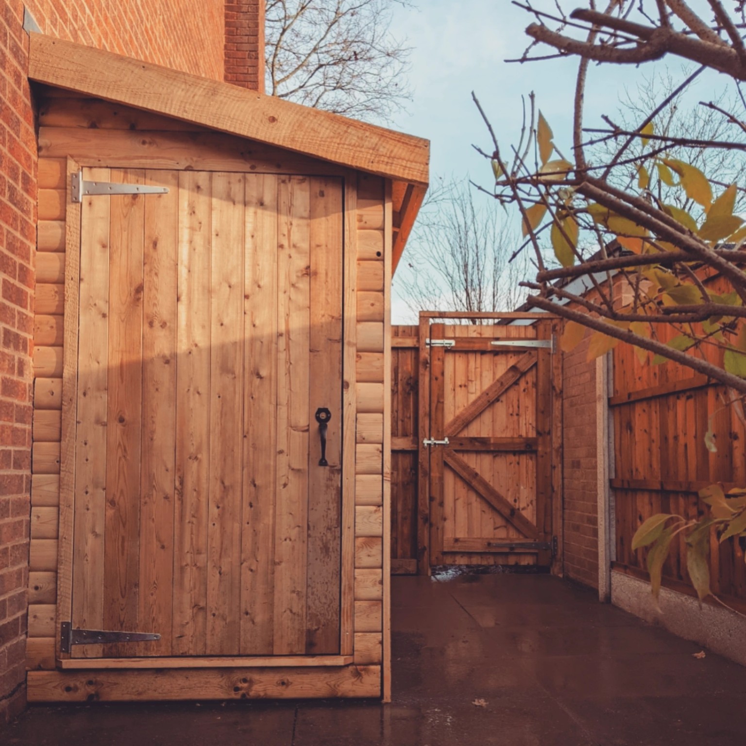 Bespoke timber gate and matching store alongside a brick house