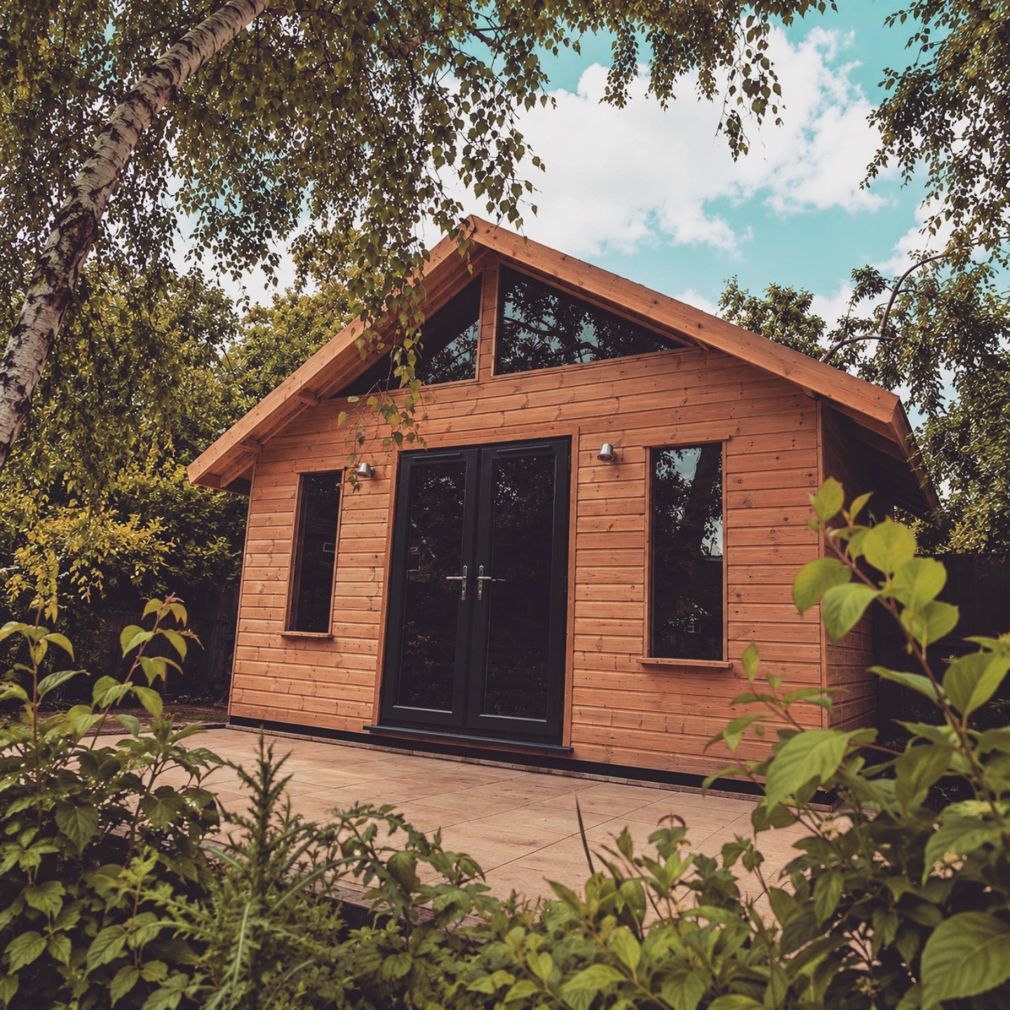 Pitched-roof timber garden room with black French doors and gable glazing
