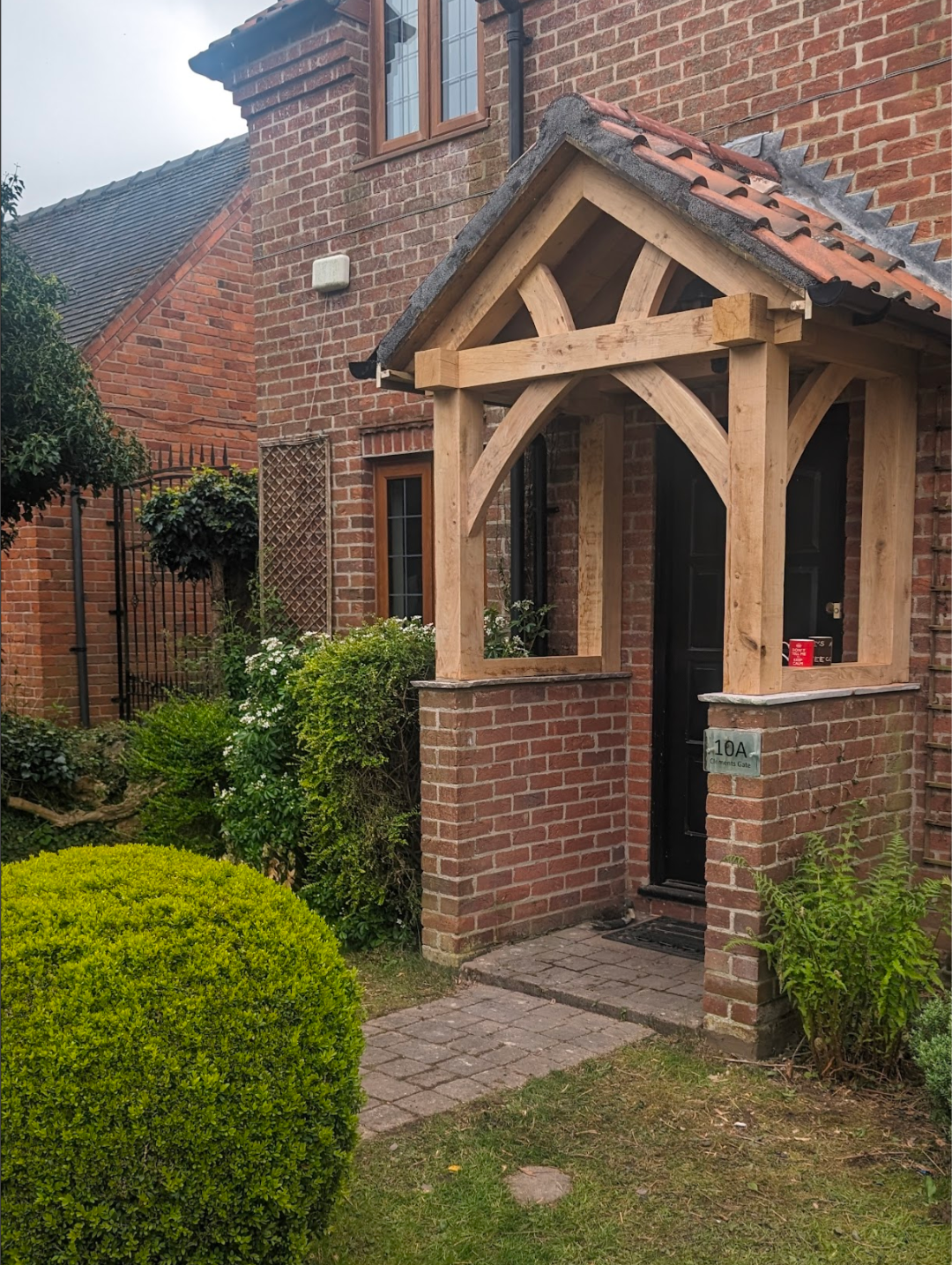 Oak-framed entrance porch with brick bases and a tiled pitched roof